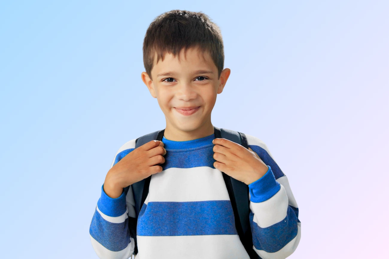 Menino com mochila sorrindo na escola